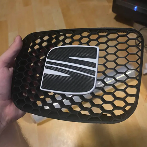 Biele logo SEAT s carbonovým povrchom